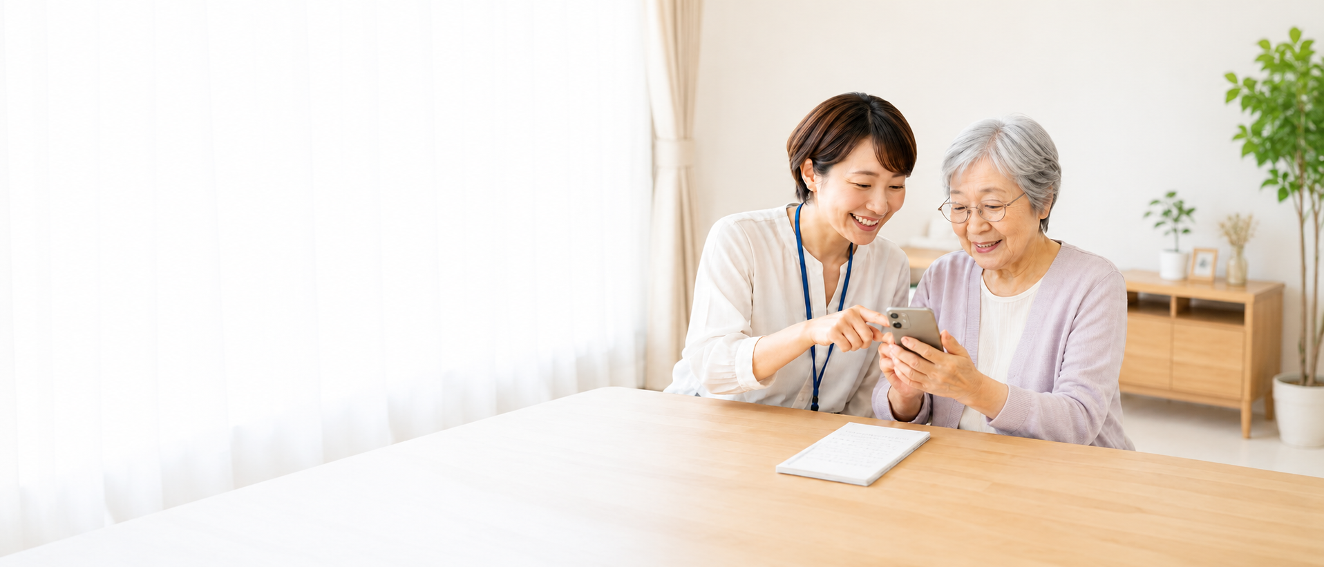 スマホの操作を一緒に確認する女性スタッフとシニア女性